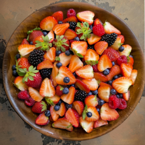 A wooden bowl brimming with a vibrant assortment of sliced strawberries, whole blackberries, raspberries, and blueberries. Our Berry Bonanza is bursting with goodness, offering fresh and colorful fruits that deliver an appetizing and health-boosting experience. Perfect for your fruit salads, juices, snacks, smoothies, whole fruit packs, and desserts. Enjoy the vitality of nature while supporting eco-friendly choices!