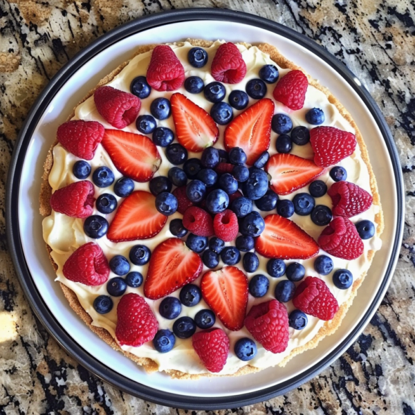 Indulge in our vibrant Berry Bliss Pizza, bursting with goodness and artfully arranged for a feast for your eyes and palate. This colorful fruit tart features sliced strawberries, raspberries, and blueberries atop a creamy filling, all resting on an eco-friendly white plate. Fresh from the granite countertop of Zestful Blends' kitchen, this delightful dessert is not only a visual masterpiece but also rich in health benefits. Perfectly crafted to bring you the freshest flavors and nutrients!