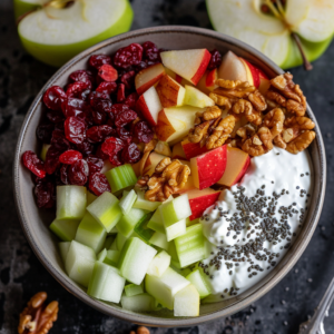 Experience a bowl bursting with goodness—our Apple & Cranberry Crunch! This vibrant medley features diced green and red apples, dried cranberries, chopped walnuts, crisp celery, creamy cottage cheese, and power-packed chia seeds. Each bite offers a delightful balance of crunch and sweet-tart flavors. Surrounded by fresh green apples and savory walnut pieces, this nutritious blend is perfect for rejuvenating your day. At Zestful Blends, we’re committed to health and sustainability with every delicious creation!