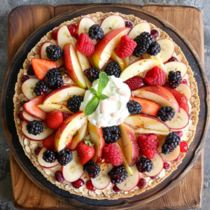 Feast your eyes on our Summer Berry Medley Pizza, a vibrant burst of goodness! Nestled on a dark plate atop an elegant wooden board, this masterpiece features apple slices, strawberries, raspberries, and blackberries—all bursting with freshness. A dollop of whipped cream adorned with mint leaves graces the center for a delightful finish. Our eco-friendly oat-sprinkled crust adds a wholesome crunch to this nutritious delight. Dive into the flavors of Zestful Blends and savor every health-packed bite!