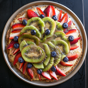 Discover the vibrant Kiwi & Berry Carnival Pizza from Zestful Blends! This colorful fruit tart, bursting with goodness, features sliced kiwis, juicy strawberries, and plump blueberries arranged in a delightful circular pattern on a sleek metallic plate. Revel in the fresh assortment of berries atop our creamy base—a true carnival of flavors. Each bite delivers a refreshing and nutritious experience that’s as eco-friendly as it is delicious. Indulge in this appetizing treat that's perfect for any occasion! #ZestfulBlends #FreshnessRedefined