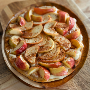 Indulge in Zestful Blends' Apple Cinnamon Delicacy Pizza, a vibrant treat bursting with goodness! A wooden platter cradles this freshly baked sensation featuring thinly sliced, tender apples sprinkled with fragrant cinnamon atop a lightly golden crust. This delightful creation not only offers the perfect balance of warmth and sweetness but also embodies our commitment to fresh, wholesome ingredients. Experience the healthy, eco-friendly choice for your palate!