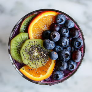 Dive into the Berry Citrus Surprise smoothie bowl from Zestful Blends, bursting with goodness and vibrant colors! This delectable creation features fresh blueberries, zesty sliced kiwi, juicy orange segments, and a sprinkle of health-boosting chia seeds. Its rich purple hue hints at a luscious blend of berries, elevated by a refreshing citrus twist. Set against an elegant marble backdrop that accentuates its clean presentation, each spoonful of this smoothie bowl is not only a feast for your taste buds but also packed with essential nutrients. Enjoy a deliciously healthy treat that's as kind to the planet as it is to you!