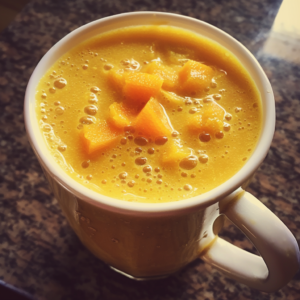 A tantalizing close-up of a ceramic mug brimming with our **Citrus Glow Smoothie**, bursting with the freshness of zesty citrus and luscious chunks of ripe mango. This vibrant yellow-orange elixir embodies health and vitality, glowing brilliantly against a stylishly speckled dark countertop. At Zestful Blends, we infuse every sip with wholesome ingredients for maximum enjoyment and nourishment. Embrace the eco-friendly goodness in every delightful gulp!