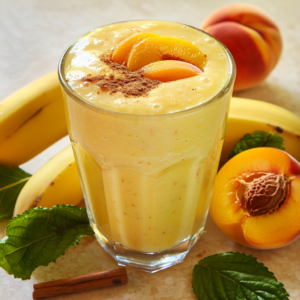 Experience the vibrant health benefits with our Sunny Peach Delight! This tall, refreshing glass is bursting with goodness, expertly garnished with luscious peach slices and a sprinkle of warm cinnamon. Surrounding it is a medley of fresh bananas, whole peaches, and tender peach slices nestled among green leaves on a sun-kissed light surface. At Zestful Blends, we’re committed to delivering the freshest fruit salads, invigorating juices, wholesome snacks, nutrient-packed smoothies, convenient whole fruit packs, and decadent yet healthy desserts. Enjoy the taste of wellness in every sip while supporting eco-friendly practices!